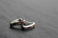 Pair of silver hoop earrings with colorful gemstones on a dark surface