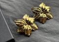 Pair of gold floral earrings on a dark gray background