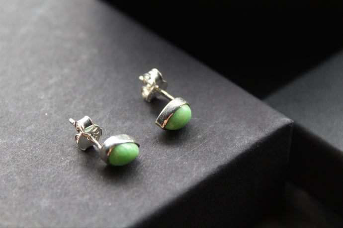 Pair of green stud earrings on a dark surface